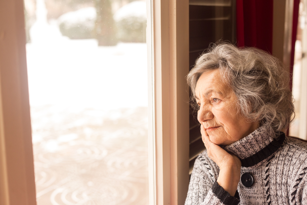 Woman looks out window on cold winter day 