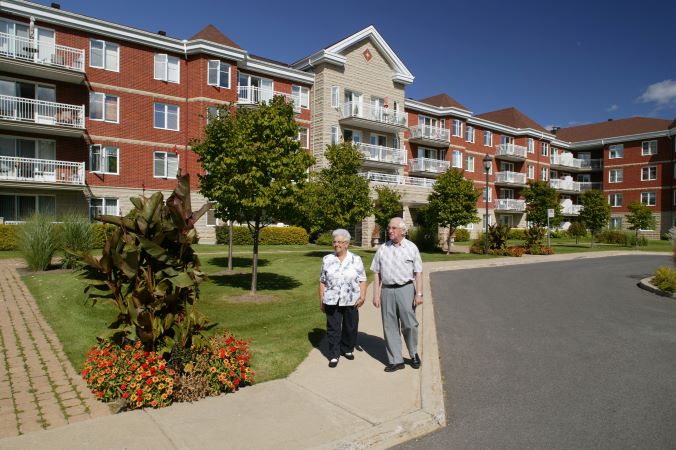 older couple walk outside apartment complex 