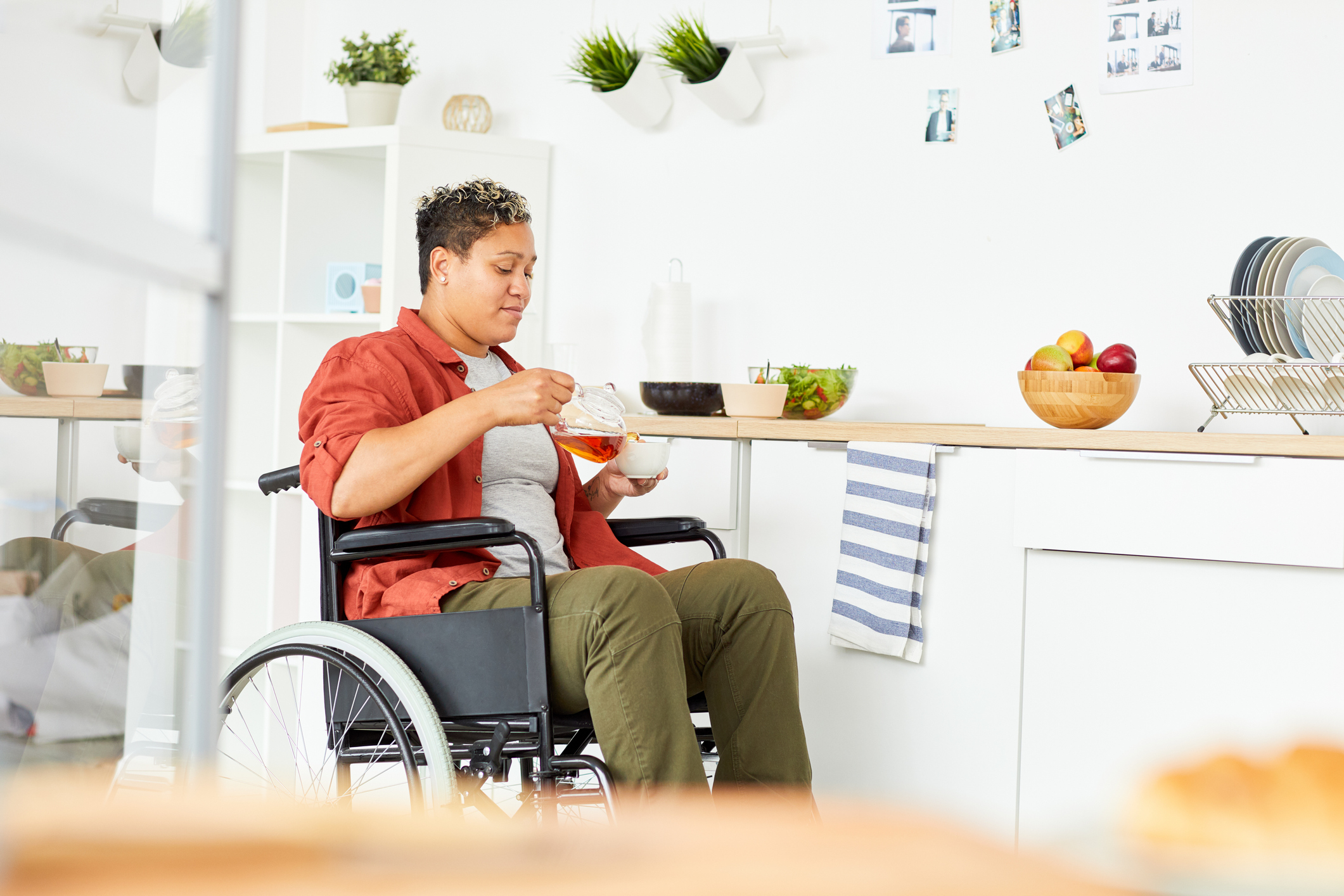 woman who uses wheelchair pours tea in a kitchen