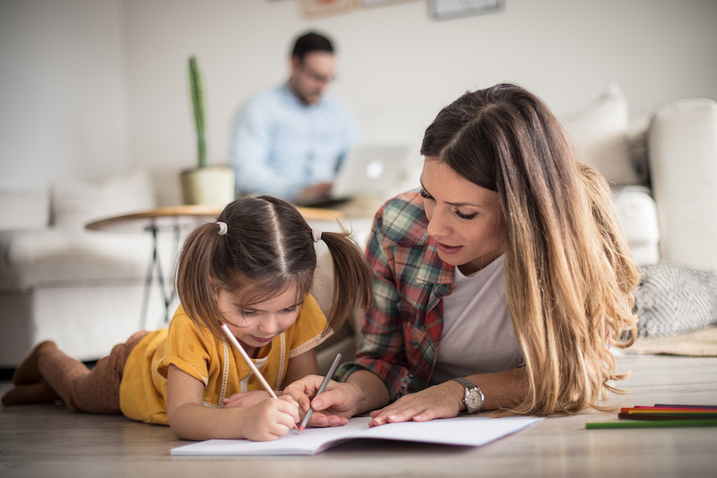 An adult with a child writing in a book.