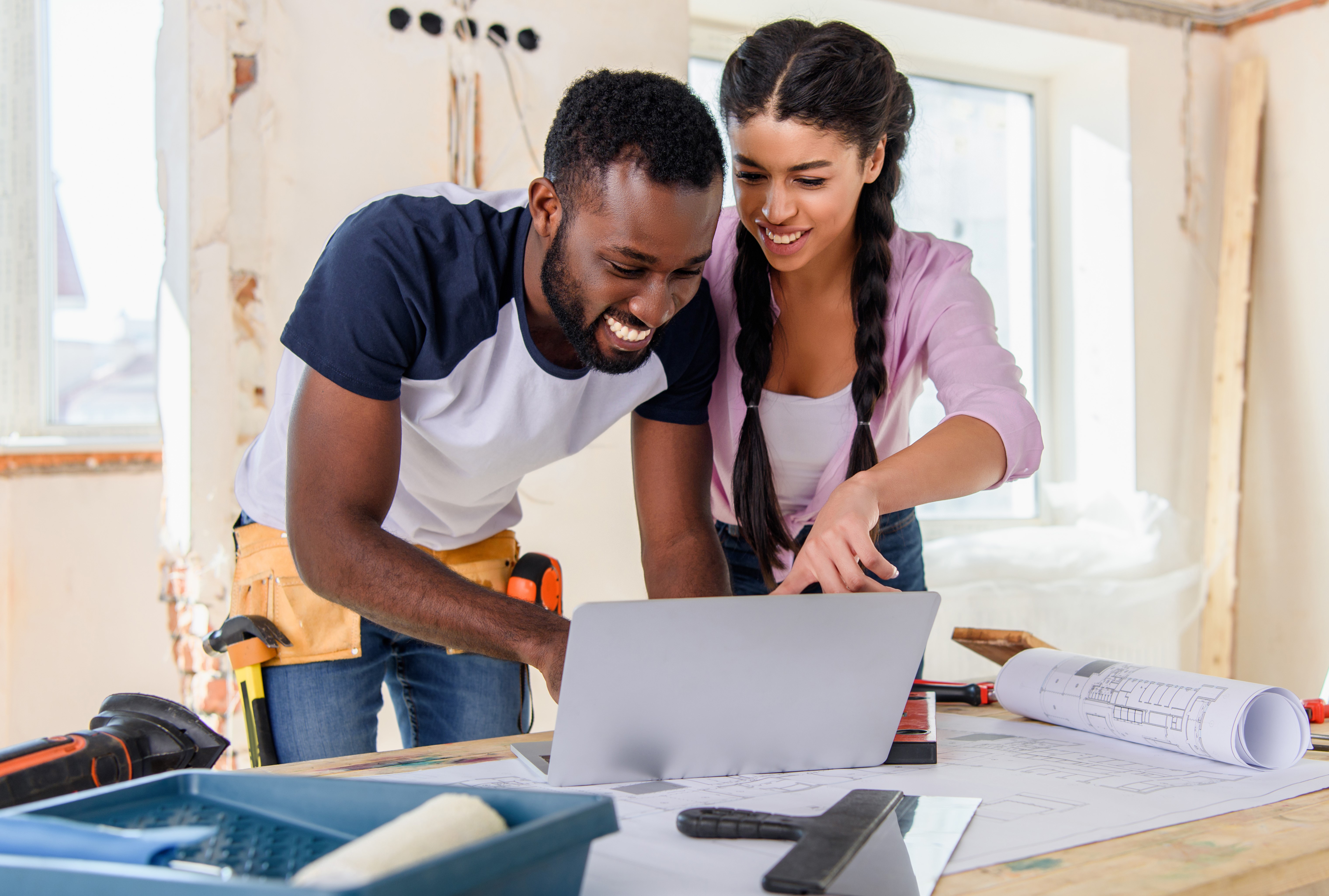 Couple discussing renovation plans while examining blueprints for their home.