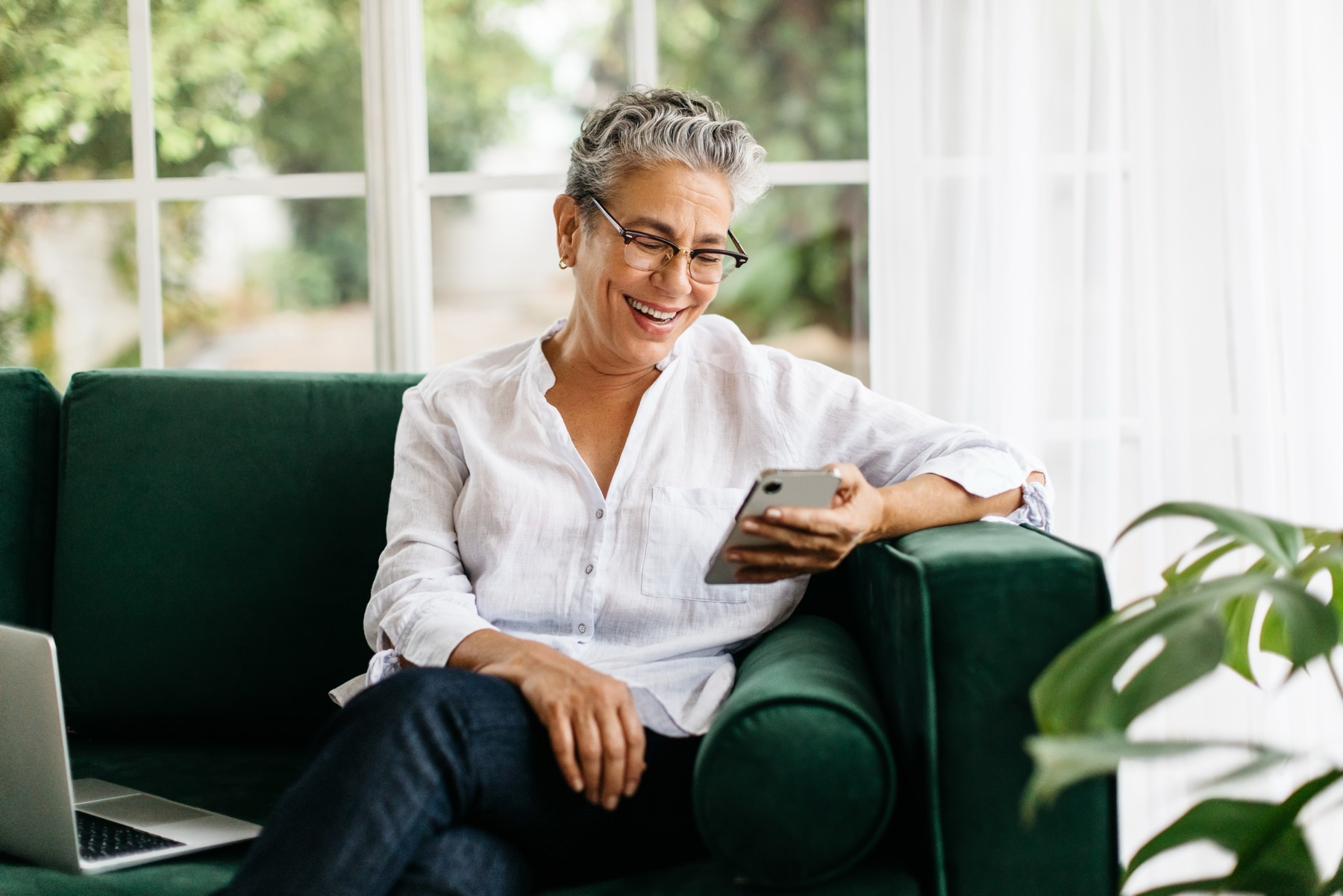 senior sitting on couch holding mobile phone.